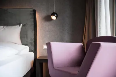 a bedroom with a bed and a purple chair at Hotel - Appartements Schmied Hans in Schenna