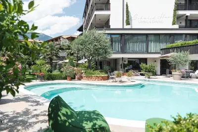 a swimming pool in front of a building at Hotel - Appartements Schmied Hans in Schenna