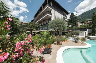 a hotel with a swimming pool and flowers at Hotel - Appartements Schmied Hans in Schenna