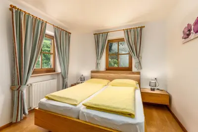 a bedroom with a bed and two windows at Nussbaumerhof in Bressanone