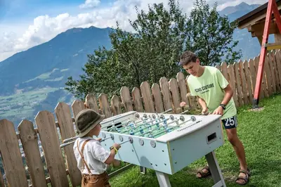 a man and a child playing with a foosball table at Nussbaumerhof in Bressanone