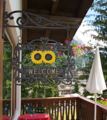 a welcome sign on a balcony with a sunflower on it at Hotel Villa Nevada in Cortina dʼAmpezzo