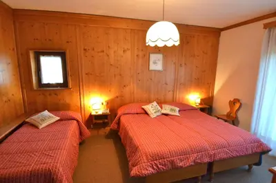 a bedroom with two beds and a chandelier at Hotel Villa Nevada in Cortina dʼAmpezzo