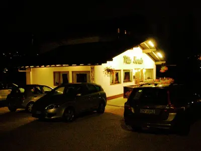 two cars parked in front of a building at night at Hotel Villa Nevada in Cortina dʼAmpezzo