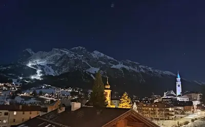 a view of a city at night with a mountain at Hotel Panda Cortina- ricarica auto elettriche in Cortina dʼAmpezzo