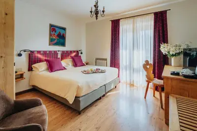 a bedroom with a large bed with purple pillows at Hotel Panda Cortina- ricarica auto elettriche in Cortina dʼAmpezzo