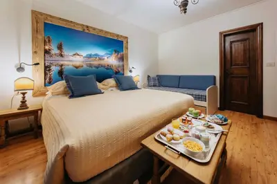 a bedroom with a large bed with a tray of food at Hotel Panda Cortina- ricarica auto elettriche in Cortina dʼAmpezzo