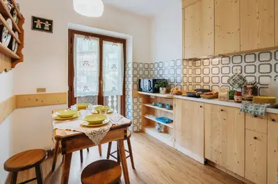 a kitchen with a table and some chairs and a counter at Hotel Panda Cortina- ricarica auto elettriche in Cortina dʼAmpezzo