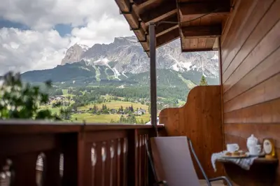 a room with a balcony with a view of a mountain at Hotel Panda Cortina- ricarica auto elettriche in Cortina dʼAmpezzo
