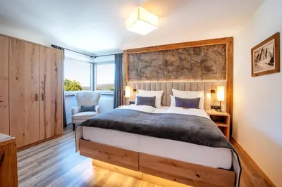 a bedroom with a large bed and a chair at Apartment Sella in Siusi