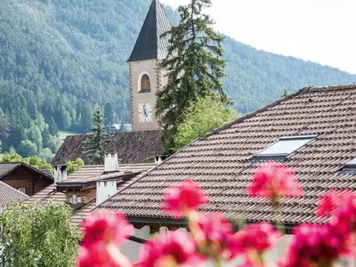 a church with a clock tower in the background with flowers at Apartment Sella in Siusi