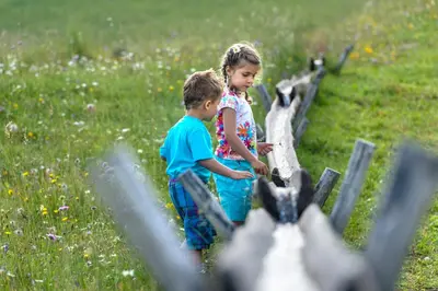 a boy and a girl standing next to a fence at Apartment Sella in Siusi