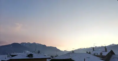 a city with snow covered roofs and mountains in the background at Casa Lassù in Carano