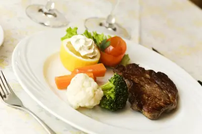 a white plate of food with meat broccoli and vegetables at Hotel Löwenwirt in Cermes