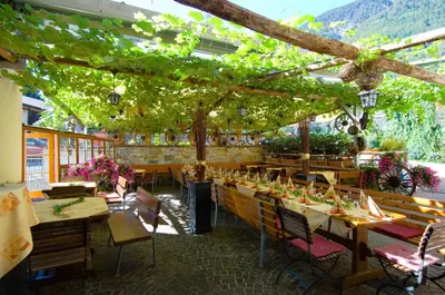 a restaurant with tables and chairs and vines at Hotel Löwenwirt in Cermes