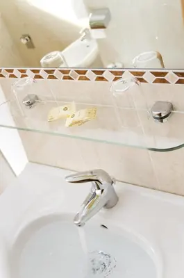 a bathroom sink with a glass shelf above it at Hotel Löwenwirt in Cermes