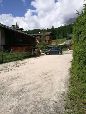 a car parked on a dirt road next to a building at La Roncolina in Cortina dʼAmpezzo