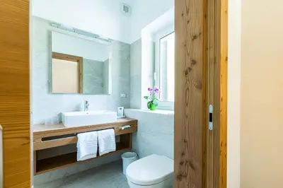 a bathroom with a sink and a toilet and a mirror at Zur Mühle Wohlfühloase in Trodena