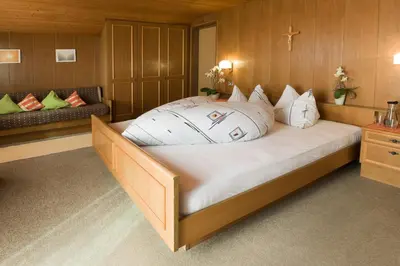 a large bed in a room with a cross on the wall at Garni Reider in Meltina