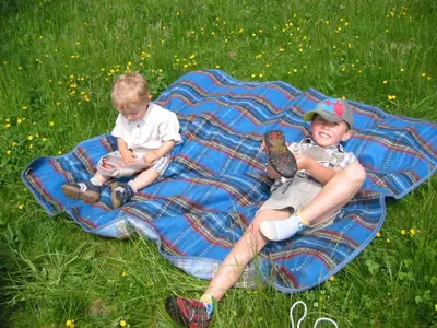 two young boys sitting on a blanket in the grass at Garni Reider in Meltina