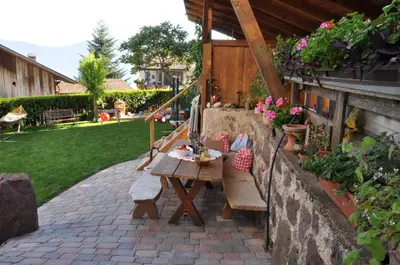 a patio with a wooden table and bench in a yard at Garni Reider in Meltina
