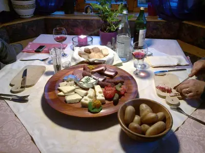 a table with a plate of food and glasses of wine at Garni Reider in Meltina