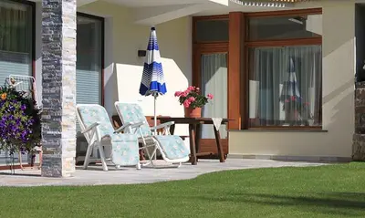 a patio with a table and chairs and an umbrella at Villa Tanja in Castelrotto