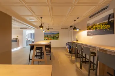 a bar in a room with stools and paintings on the wall at Vineus Tramin in Termeno