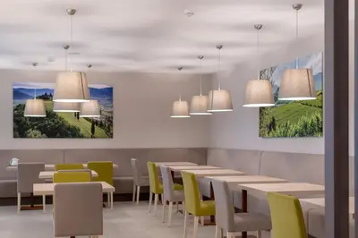 a dining room with tables and chairs and paintings at Vineus Tramin in Termeno