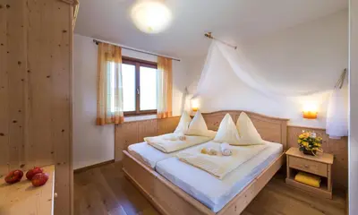 a bedroom with a bed with white sheets and a window at Apartments Elisir in Castelrotto