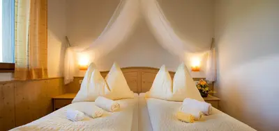 a bedroom with two beds with white sheets and pillows at Apartments Elisir in Castelrotto