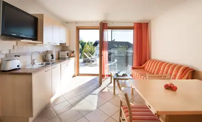 a kitchen and living room with a couch and a table at Apartments Elisir in Castelrotto