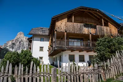 a wooden house with a fence in front of it at Nei Y Suredl NeveSole in Corvara in Badia