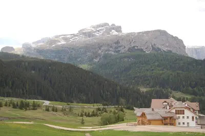 a house in a field with a mountain in the background at Nei Y Suredl NeveSole in Corvara in Badia