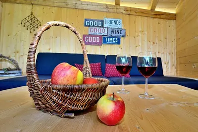 a basket of apples and two glasses of wine on a table at Appartements Mayrhof in Bressanone