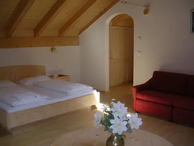 a bedroom with a bed and a red couch at Garni La Tambra in Selva di Val Gardena