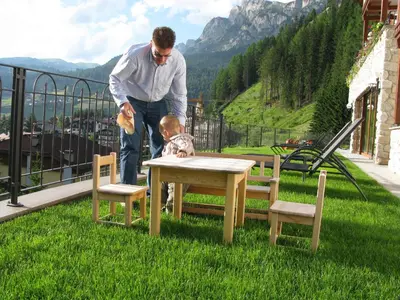 a man standing next to a child sitting at a table at Garni La Tambra in Selva di Val Gardena