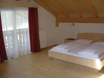 a bedroom with a bed and a red curtain at Garni La Tambra in Selva di Val Gardena