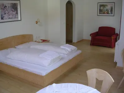 a bedroom with a bed and a red chair at Garni La Tambra in Selva di Val Gardena