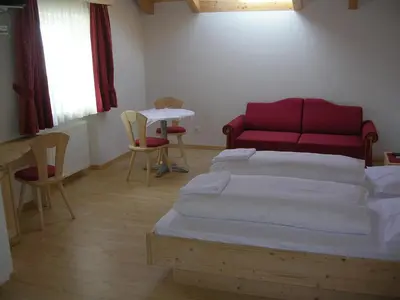 a bedroom with a bed and a table and chairs at Garni La Tambra in Selva di Val Gardena