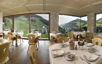 a restaurant with tables and chairs and a large window at Garni La Tambra in Selva di Val Gardena