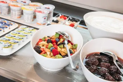 a buffet with bowls of fruit and other desserts at Garni Hotel Miara - Your Dolomites Home in Selva di Val Gardena