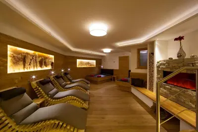 a room with a row of couches and a fireplace at Garni Hotel Miara - Your Dolomites Home in Selva di Val Gardena
