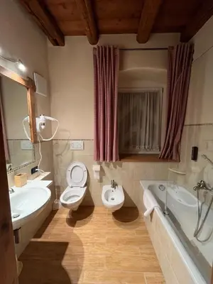 a bathroom with two toilets and a sink and a tub at Castel Madonna in San Martino di Castrozza