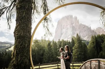 a bride and groom standing under an arch with a mountain at Cendevaves Alpine Silence in Santa Cristina in Val Gardena