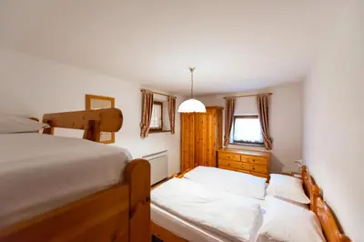 a bedroom with two beds and a window at Appartamenti Majon Ladina in Vigo di Fassa