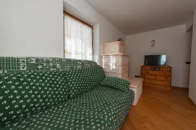 a living room with a green couch and a television at Appartamenti Majon Ladina in Vigo di Fassa