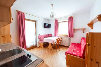 a living room with a red couch and a table at Appartamenti Majon Ladina in Vigo di Fassa