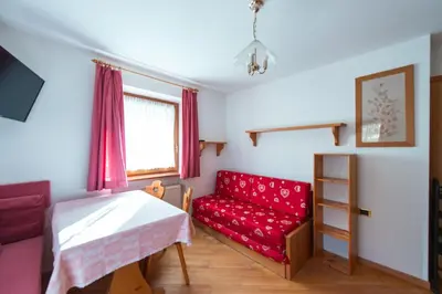 a living room with a red couch and a red chair at Appartamenti Majon Ladina in Vigo di Fassa