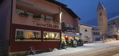 a building with a sign on it in the snow at Gasthof Salurn in Salorno sulla Strada del Vino